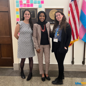 Two BikeMN staff pose with Representative Ilhan Omar in front of her office.