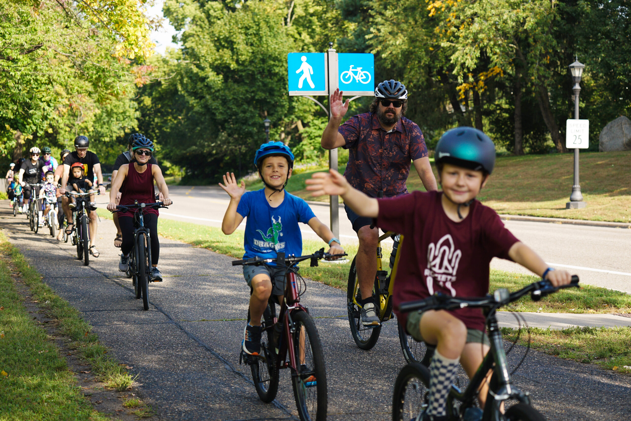 Smiling kids waving at the camera while riding bikes