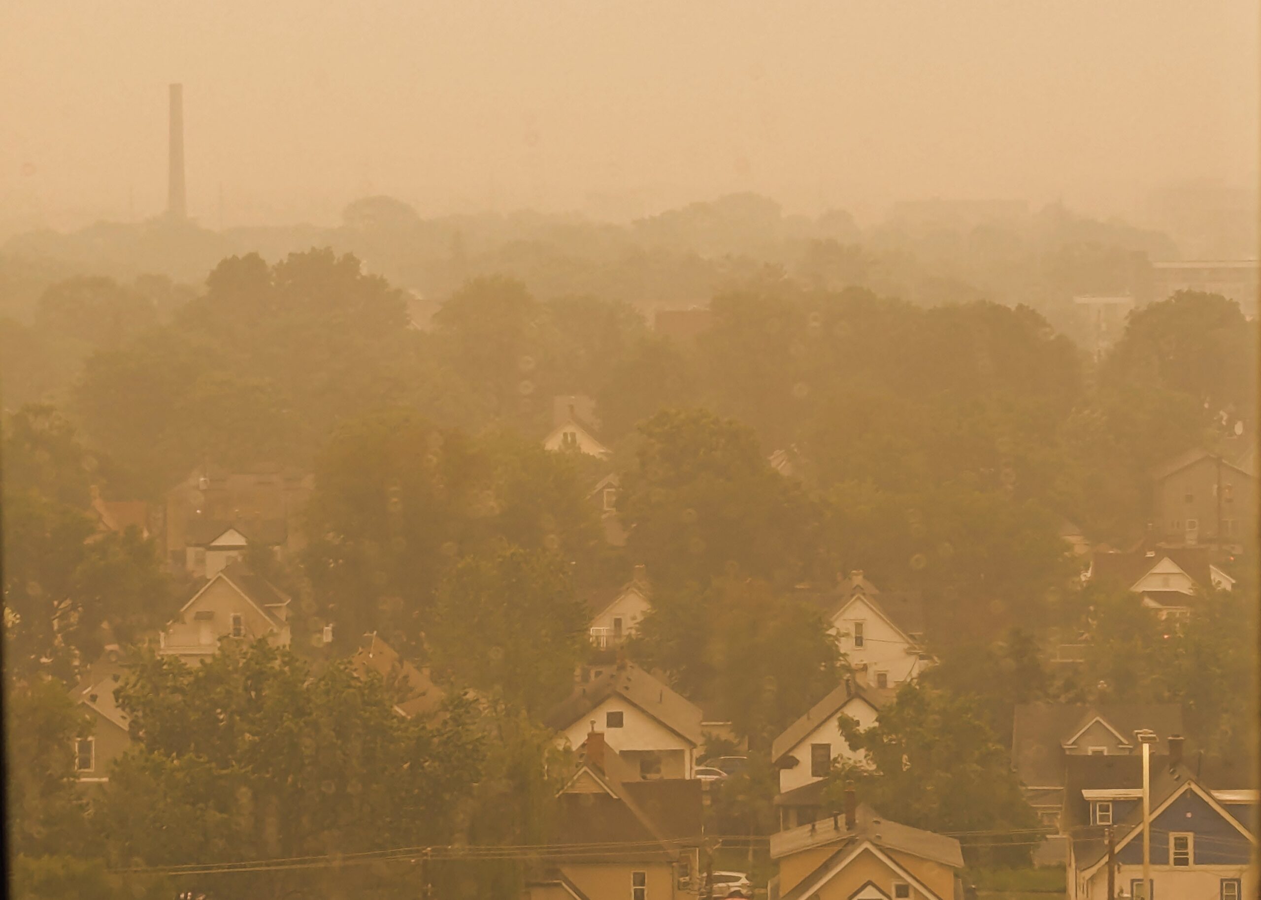 A neighborhood seen from above, inundated with wildfire smoke and orange brown light