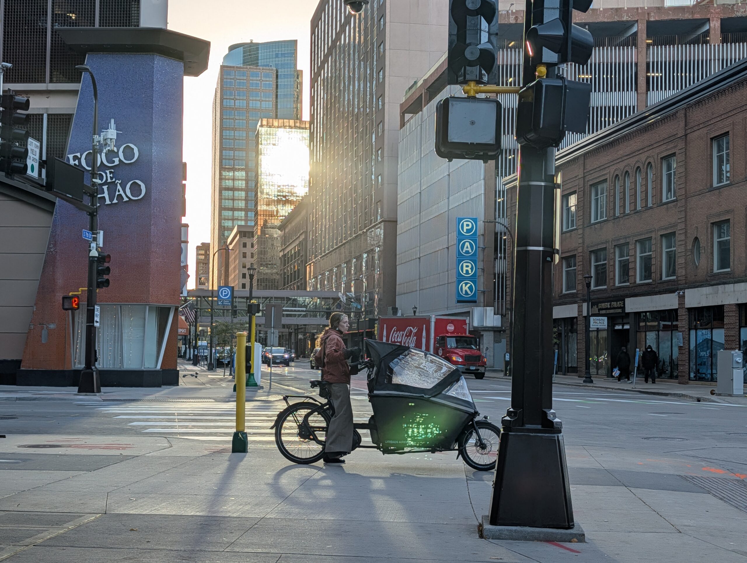 A person on a cargo bike waits to cross a street on protected bike infrastructure
