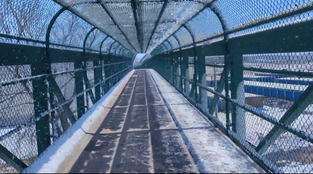 A pedestrian bridge built in 2012. Green metal, concrete path.