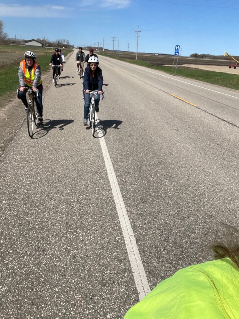 A photo taken over the shoulder by someone riding their bike, showing people riding behind along a road.